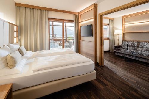 a bedroom with a large bed and a television at Lake Spa Hotel SEELEITEN in Caldaro