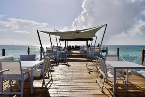 a wooden pier with tables and chairs on the beach at Beach Day at CadaquesCaribe Bayahibe in Bayahibe