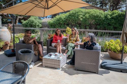 a group of women sitting in chairs under an umbrella at Hotel Boutique Aldea del Mar in Pichilemu