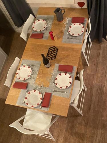 une table en bois avec des plaques blanches et des chaises rouges dans l'établissement Appartement de charme Courchevel 1550, à Courchevel