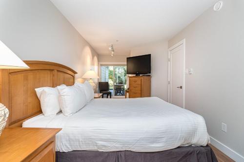 a bedroom with a white bed and a television at Pacific Shores Resort & Spa in Nanoose Bay