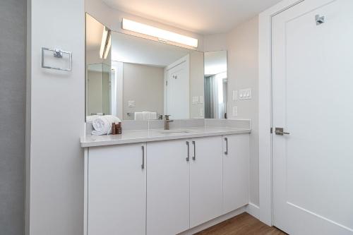 a white bathroom with a sink and a mirror at Pacific Shores Resort & Spa in Nanoose Bay