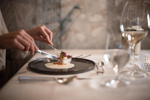 a person eating a dessert on a table with a plate at Lake Spa Hotel SEELEITEN in Caldaro
