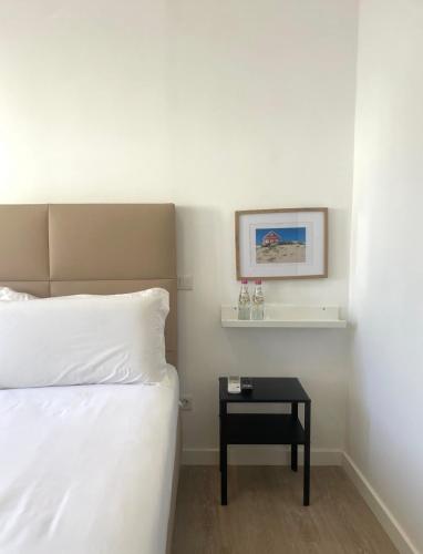 a bedroom with a white bed and a black table at Vila Alexandra in Costa da Caparica