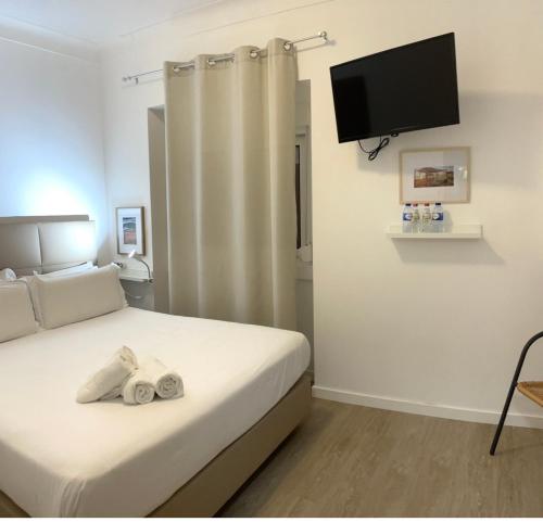 a bedroom with a bed with a flat screen tv on the wall at Vila Alexandra in Costa da Caparica