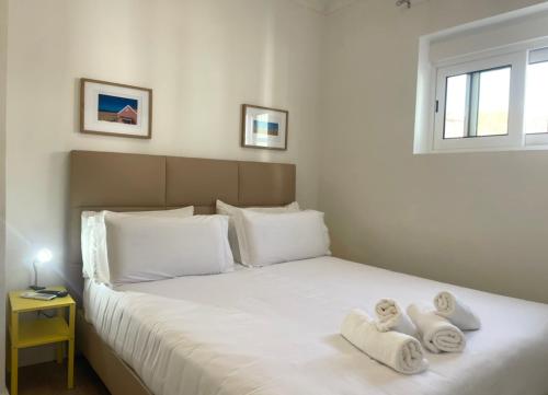 a bedroom with a large white bed with towels on it at Vila Alexandra in Costa da Caparica