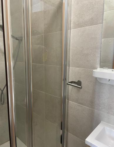 a shower with a glass door next to a sink at Vila Alexandra in Costa da Caparica
