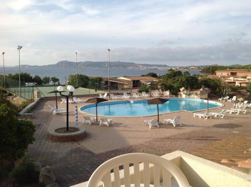 a swimming pool with chairs and a view of the water at Club Esse Residence Capo D'orso in Palau