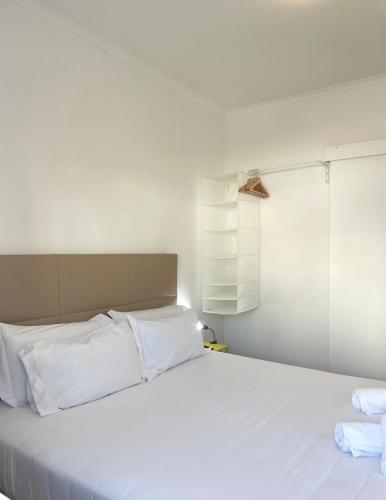 a white bed with white pillows in a room at Vila Alexandra in Costa da Caparica