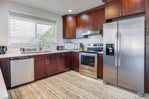 a kitchen with wooden cabinets and stainless steel appliances at Ewa Beach Apartment about 1 Mi to Puʻuloa Beach Park! in Kapolei