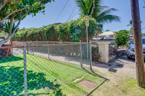 a chain link fence in a yard with a palm tree at Ewa Beach Apartment about 1 Mi to Puʻuloa Beach Park! in Kapolei