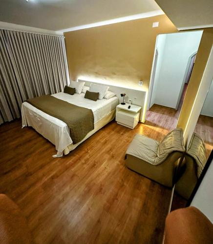 a bedroom with a large bed and a couch at Dom Ravello in Telêmaco Borba
