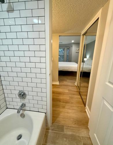 a bathroom with a bath tub and a bedroom at Aksarben Gem near UNO in Omaha