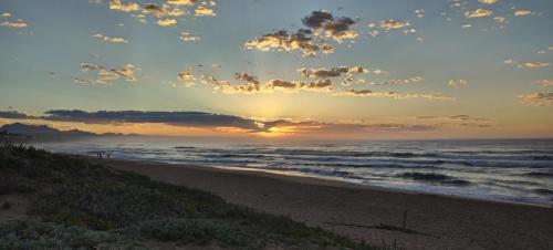 a sunset on a beach with the ocean at 1 On Wilderness in Klein Brak Rivier