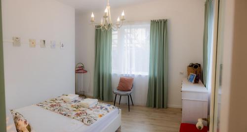 a bedroom with a bed and a chair and a window at Homey Luxury- entire house, free parking, yard in Cluj-Napoca