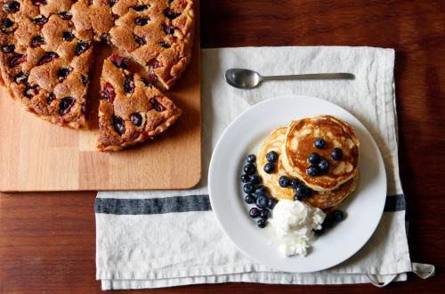 a plate of blueberry pancakes and a pie on a table at La Maison & L'atelier in Neuilly-en-Thelle