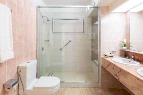 a bathroom with a shower and a toilet and a sink at Royal Islander Club Resort La Plage in Lowlands