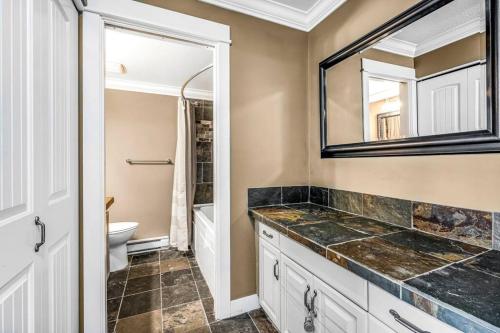 a bathroom with a sink and a toilet and a mirror at Winter Escape On Perfection - Ski In Out, Pool & Hot Tub in Big White