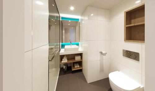 a white bathroom with a toilet and a sink at Holiday Inn Express & Suites Ghent by IHG in Ghent