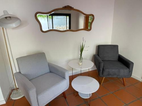 a living room with two chairs and a table and a mirror at Casa de la Flor by Posada de la Flor in Colonia del Sacramento