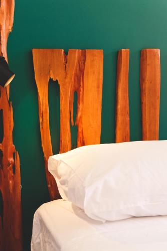 a bed with a wooden headboard with a white pillow at Hôtel les Sables in Saint-Laurent du Maroni
