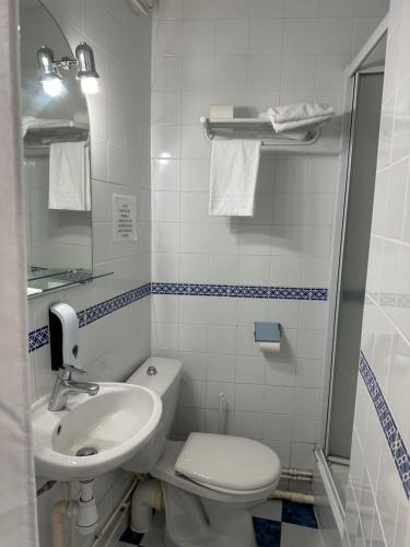 a white bathroom with a sink and a toilet at La Locomotive in Issoudun
