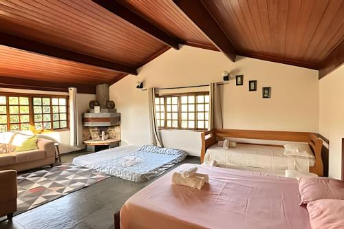 two beds in a room with a couch and a fireplace at Sítio São Francisco da saudade Refugio Conforto e Afeto na Serra de Cunha a 200m do asfalto in Cunha