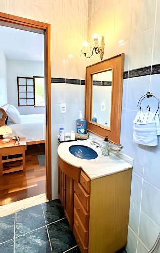 a bathroom with a sink and a mirror and a bed at Sítio São Francisco da saudade Refugio Conforto e Afeto na Serra de Cunha a 200m do asfalto in Cunha