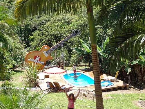 a girl standing next to a pool with a giant guitar at Sítio com piscina em Caldas da Imperatriz in Santo Amaro da Imperatriz