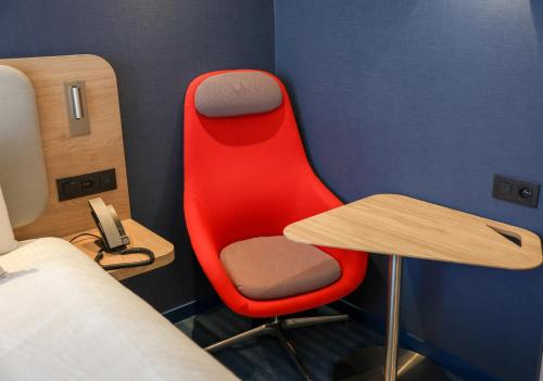 a red chair next to a table and a bed at Holiday Inn Express & Suites Ghent by IHG in Ghent