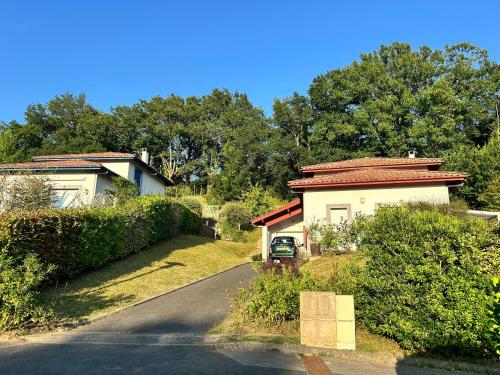 a house with a car parked next to a road at Trés belle villa 4 étoiles - 3 chambres - Terrasse et jardin in Cambo-les-Bains