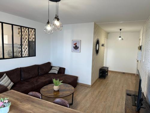 a living room with a brown couch and a table at Le Grand Parc 13 - 2 chambres - wifi - parking in Châteauroux