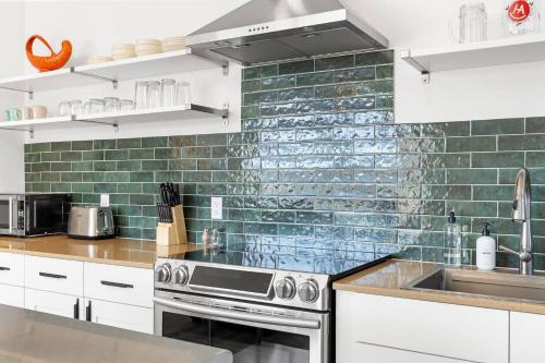 a kitchen with white cabinets and green subway tiles at Hot Tub 4 Baths Montana Themed Bike To Downtown in Livingston