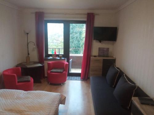 a bedroom with a living room with a couch and a window at Komfortowy pokój gościnny 300 m od morza dzielnica uzdrowisk in Kołobrzeg