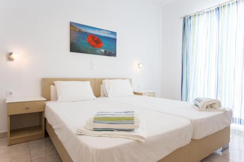 a bedroom with a white bed with towels on it at Theologos Beach in Antiparos Town