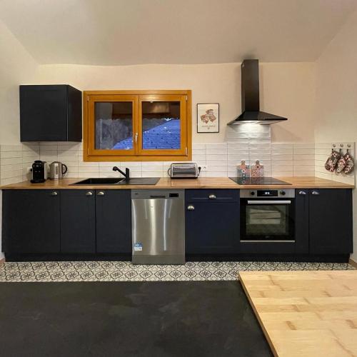 une cuisine avec des armoires bleu foncé et une fenêtre dans l'établissement Le Chalet du Meunier, à Saint-Jean-dʼAulps
