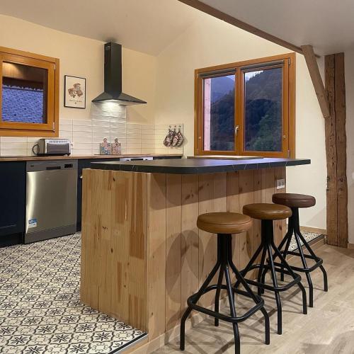 une cuisine avec trois tabourets de bar à un comptoir dans l'établissement Le Chalet du Meunier, à Saint-Jean-dʼAulps