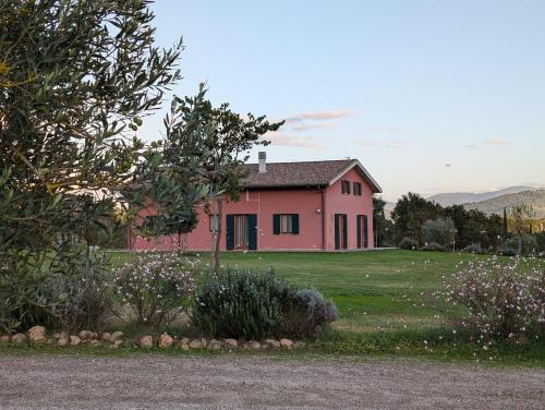 una casa rosa en medio de un campo en PODERE GRETANO casetta in maremma, en Paganico