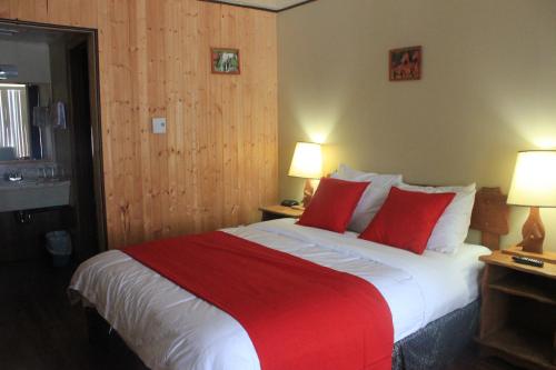 a bedroom with a large bed with red pillows at Motel Des Pays D'En Haut in Val-David