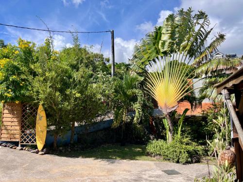a house with a surfboard leaning against a fence at Domaine Racines e Zel - Gîte PomKajou in Vieux-Fort