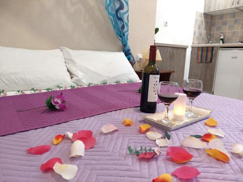 a table with a bottle of wine and a candle and flowers at Evelina Family Beach Pension a breath away from the Black Beach offer plenty of accommodation type to suit every traveler's needs-Economic Rooms-Thematic Rooms-Design Rooms-Kitchenette Rooms-Studios-Small Apartments in Perissa