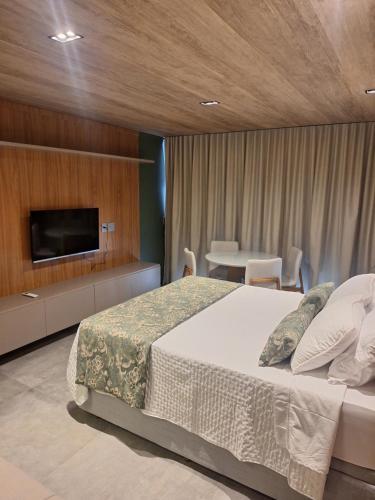 a bedroom with a bed and a tv and a table at New time Pajuçara in Maceió