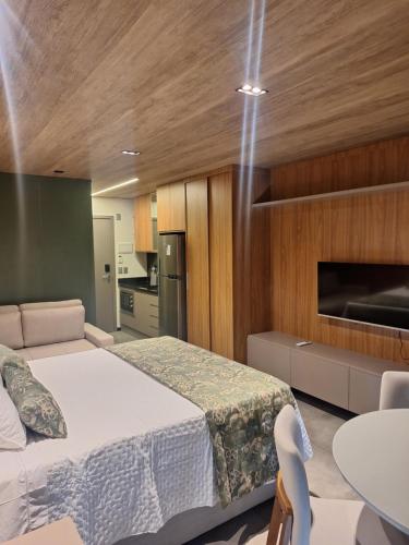 a bedroom with a bed and a table and a kitchen at New time Pajuçara in Maceió