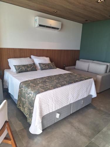 a bedroom with a large bed and a couch at New time Pajuçara in Maceió