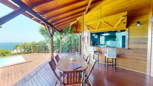 a wooden deck with a wooden table and chairs at Domaine Racines e Zel - Gîte PomKajou in Vieux-Fort