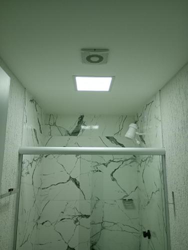a bathroom with white marble walls and a ceiling at top Suites in Saquarema