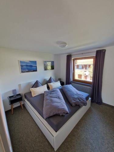 a bedroom with a bed with two pillows and a window at FeWo Chiemgau in Gstadt am Chiemsee