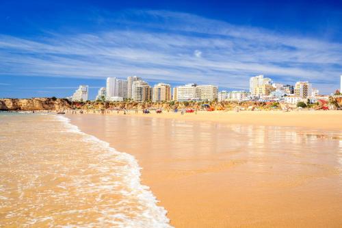 a view of a beach with a city in the background at McRamé Design Apt Sea View, Beachfront, Swimming Pool, 2BDR, 2BAR, 6 pax, Praia da Rocha in Portimão