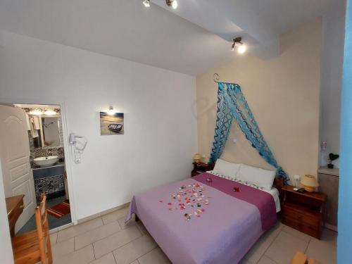 a bedroom with a purple bed with a blue canopy at Evelina Family Beach Pension a breath away from the Black Beach offer plenty of accommodation type to suit every traveler's needs-Economic Rooms-Thematic Rooms-Design Rooms-Kitchenette Rooms-Studios-Small Apartments in Perissa