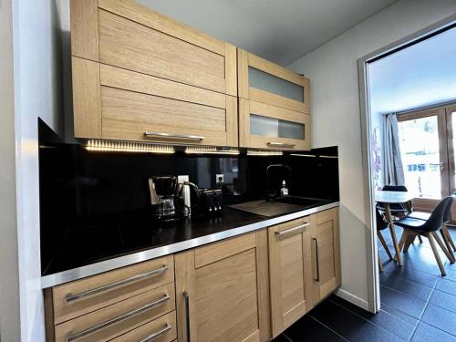 une cuisine avec des armoires en bois et un comptoir noir dans l'établissement Résidence Le Pelvoux - Résidence PELVOUX N°120 MAE-1471, à La Plagne Tarentaise